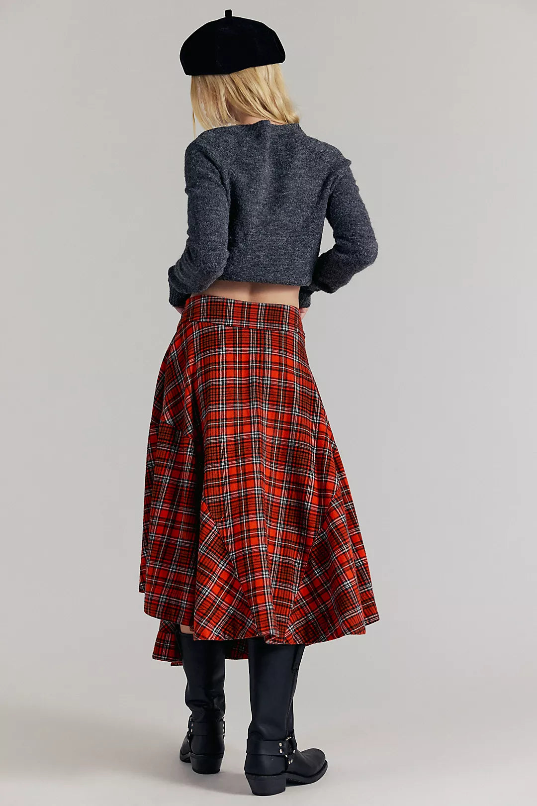 Person wearing a Free People red plaid skirt and black beret on a plain background