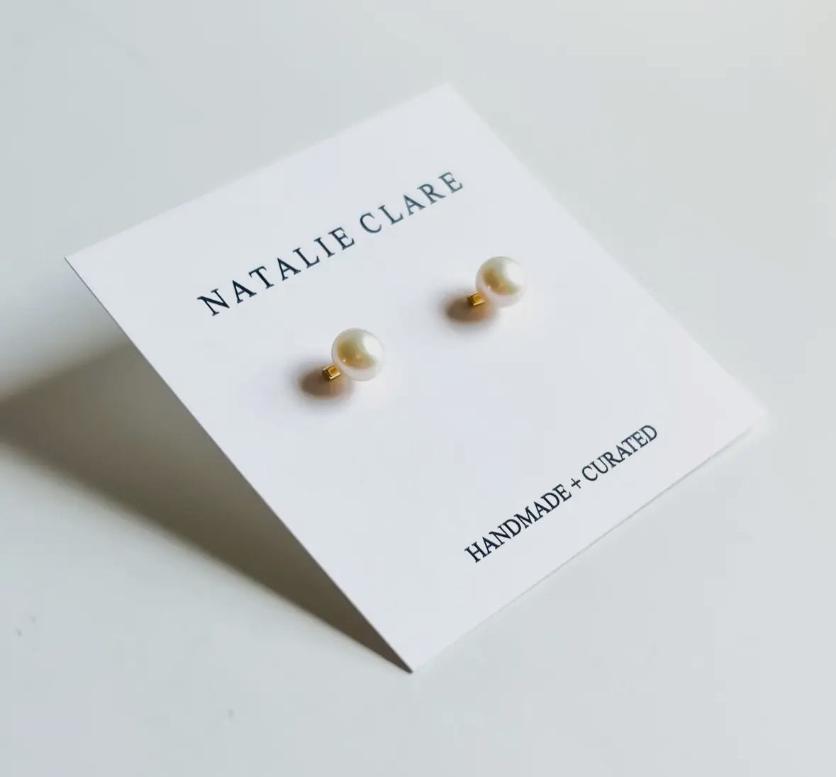 Pearl earrings on a 'Natalie Clare' branded card with a white background