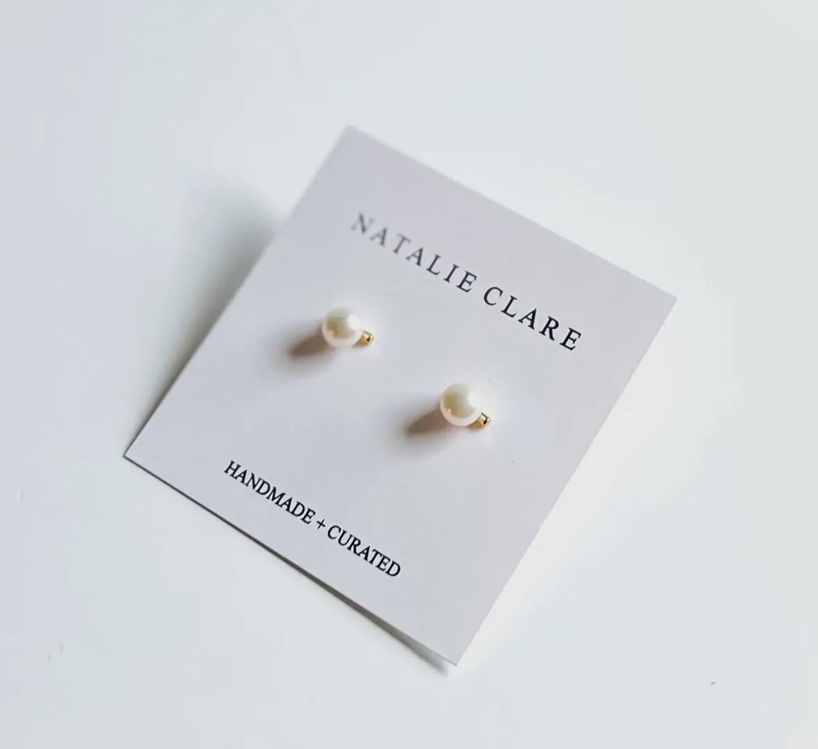 Pearl earrings on a 'Natalie Clare' branded card with a white background