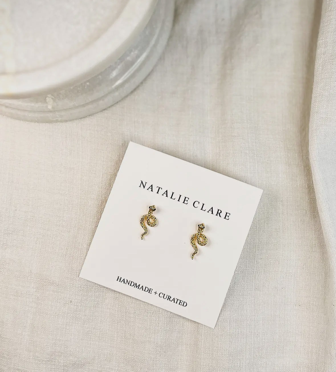 Gold seahorse earrings on a 'Natalie Clare' branded card with a beige background