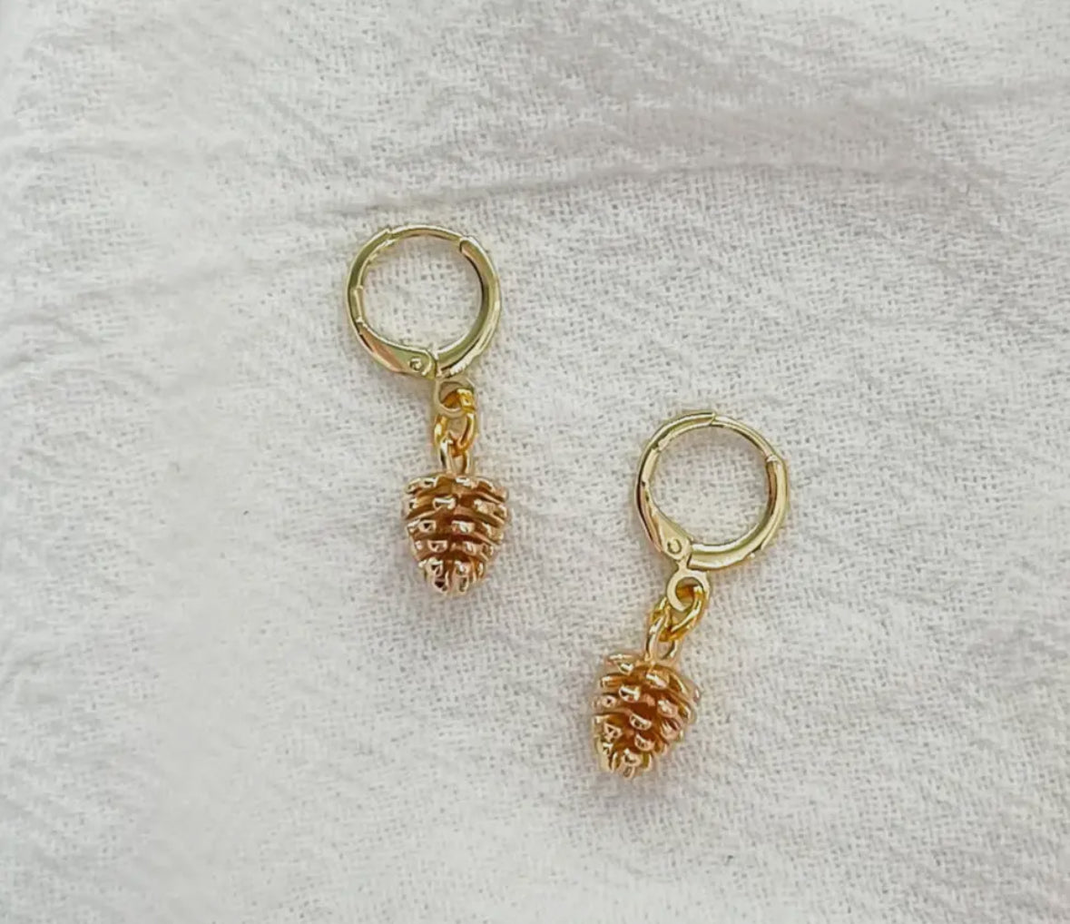 Gold hoop earrings with pinecone charms on a light gray background