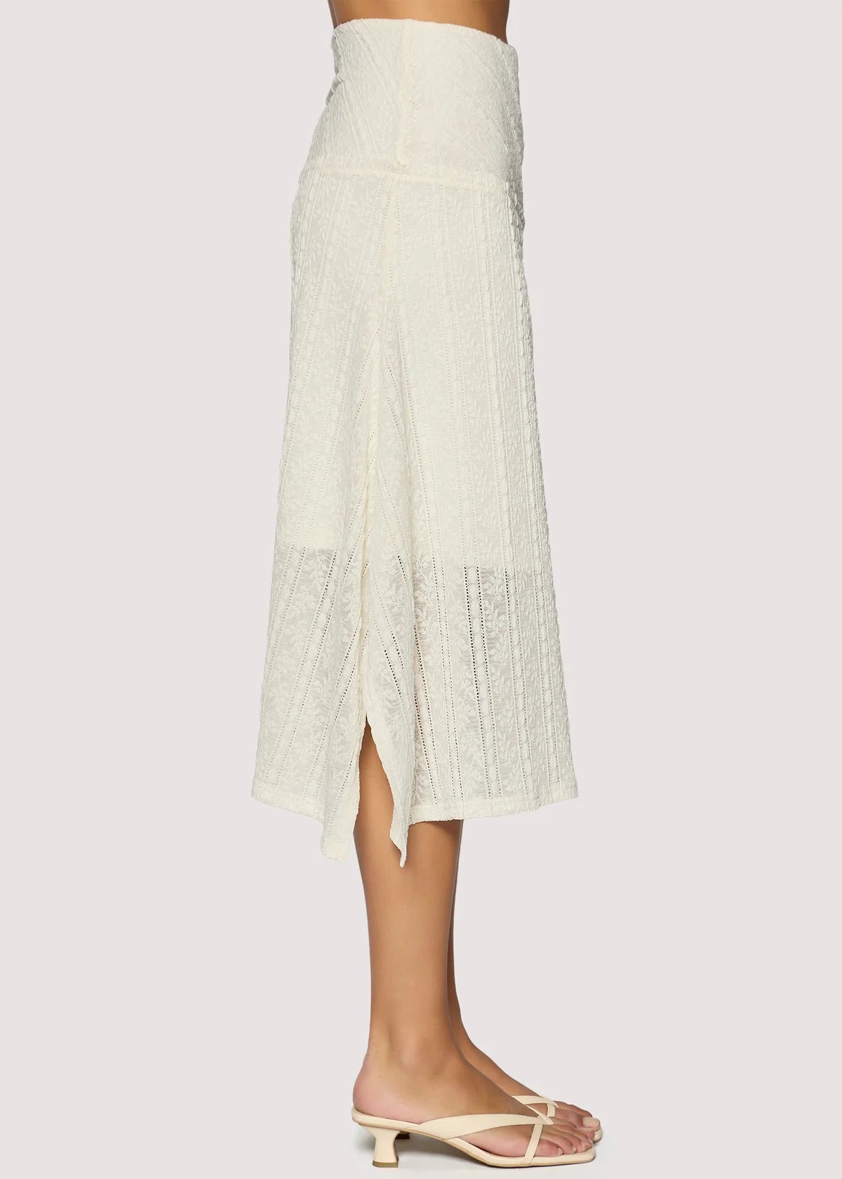 White lace skirt worn by a person on a light gray background
