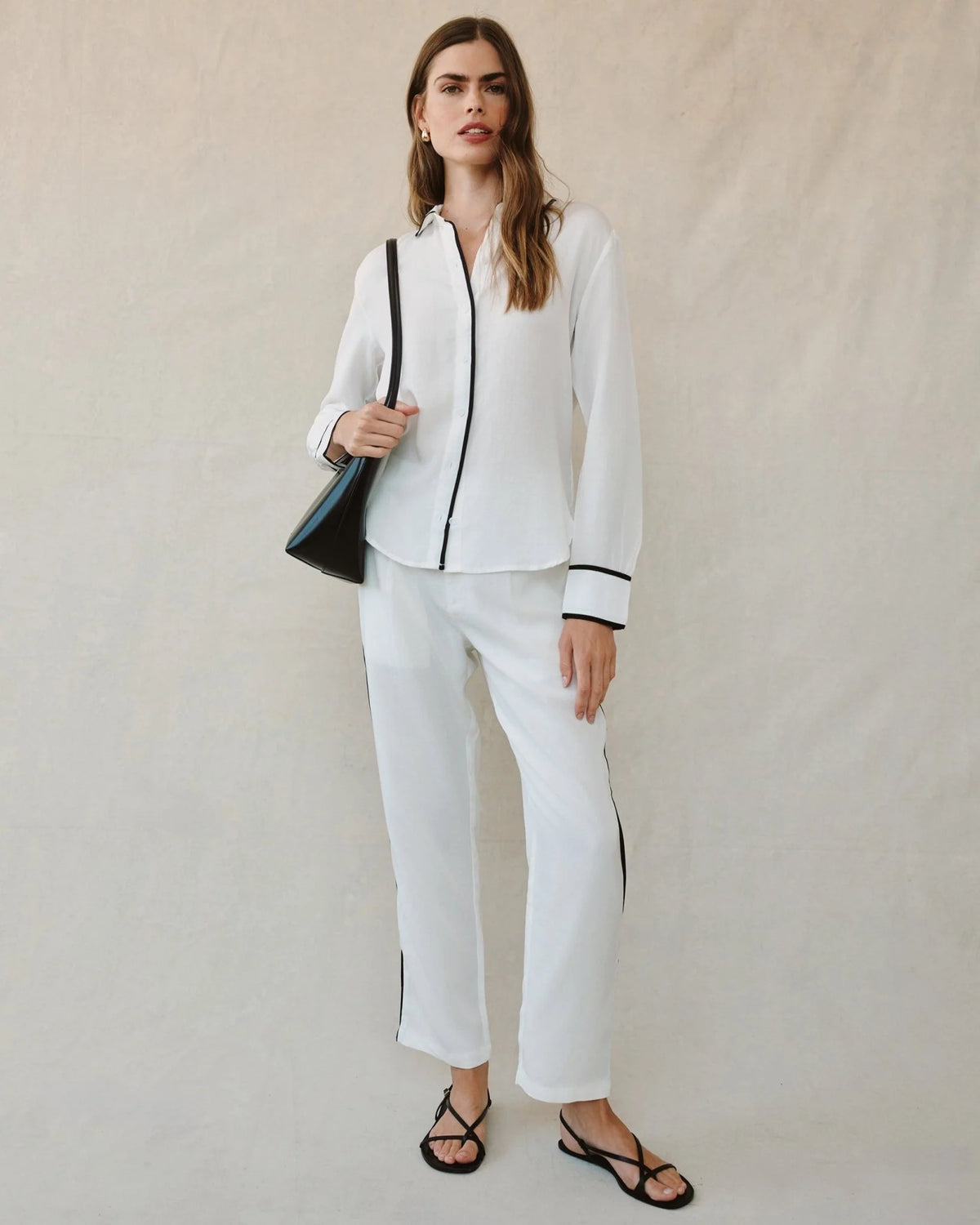 Woman wearing a white outfit with black accents against a plain background