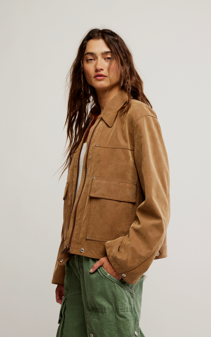 Person wearing a brown jacket and green pants against a plain background