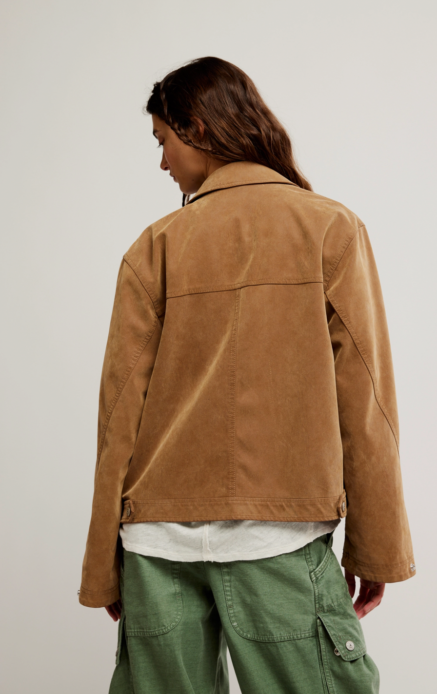 Person wearing a brown jacket and green pants on a plain background