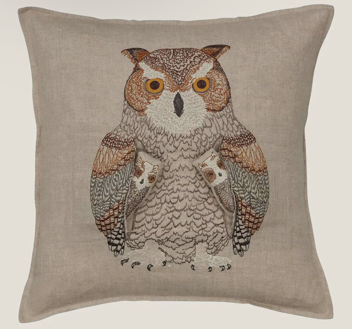 Decorative pillow with an embroidered owl design on a beige background