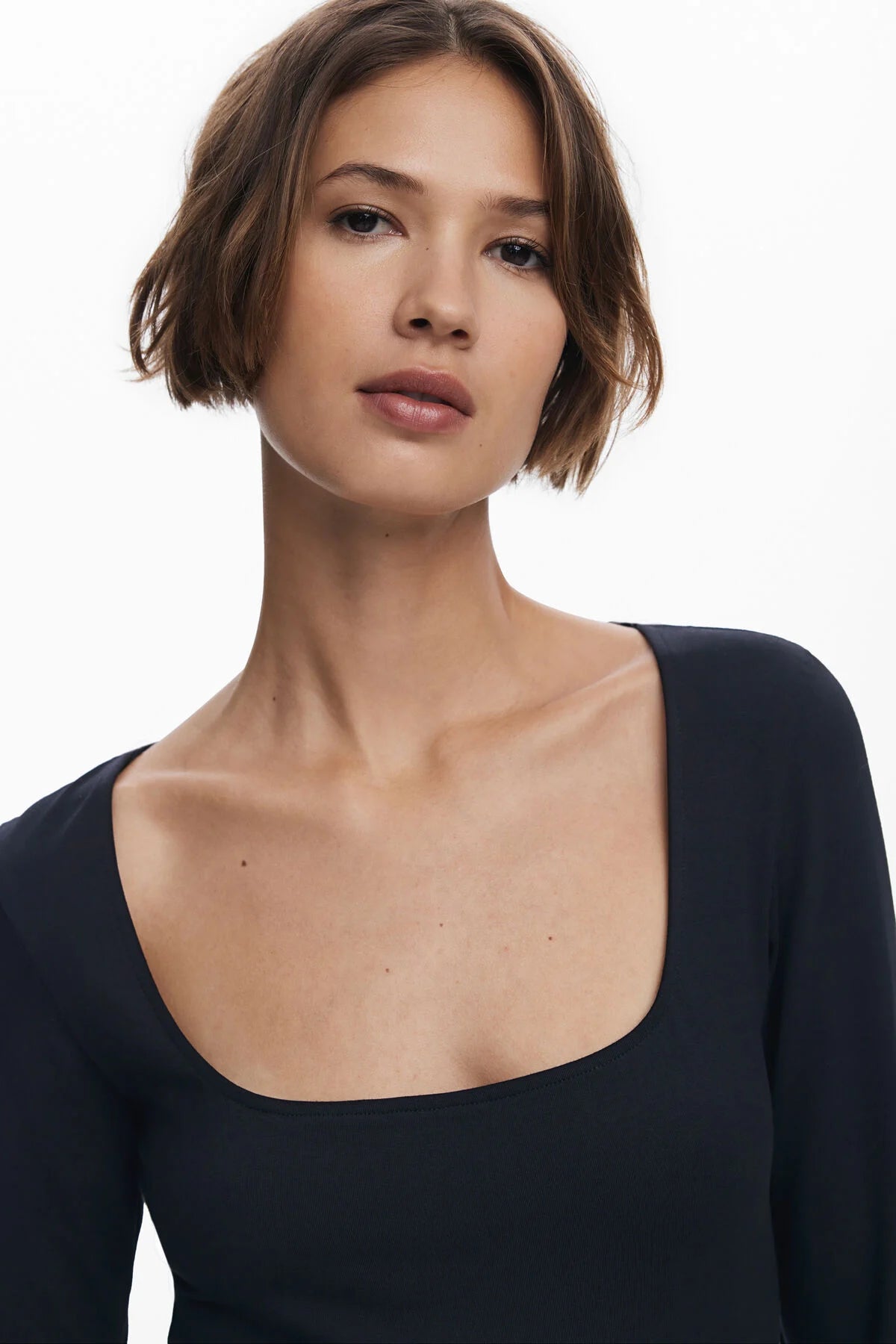 Woman wearing a black long-sleeve top against a white background