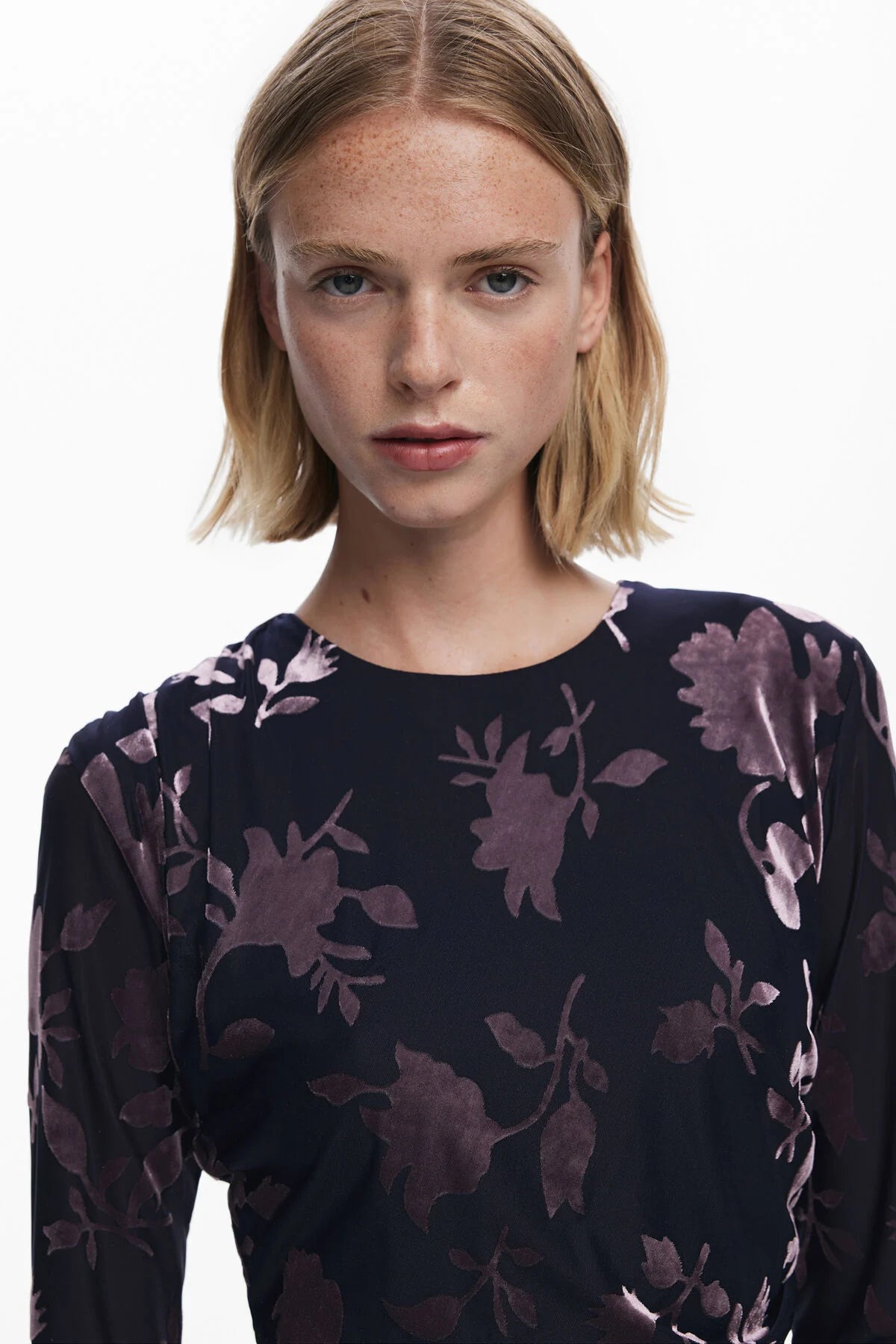 Woman wearing a dark floral patterned top on a white background