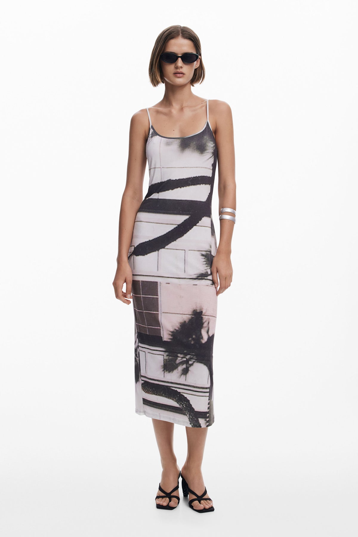 Woman wearing a sleeveless dress with abstract patterns on a white background