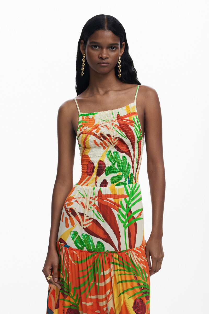 Woman wearing a colorful tropical print dress on a white background