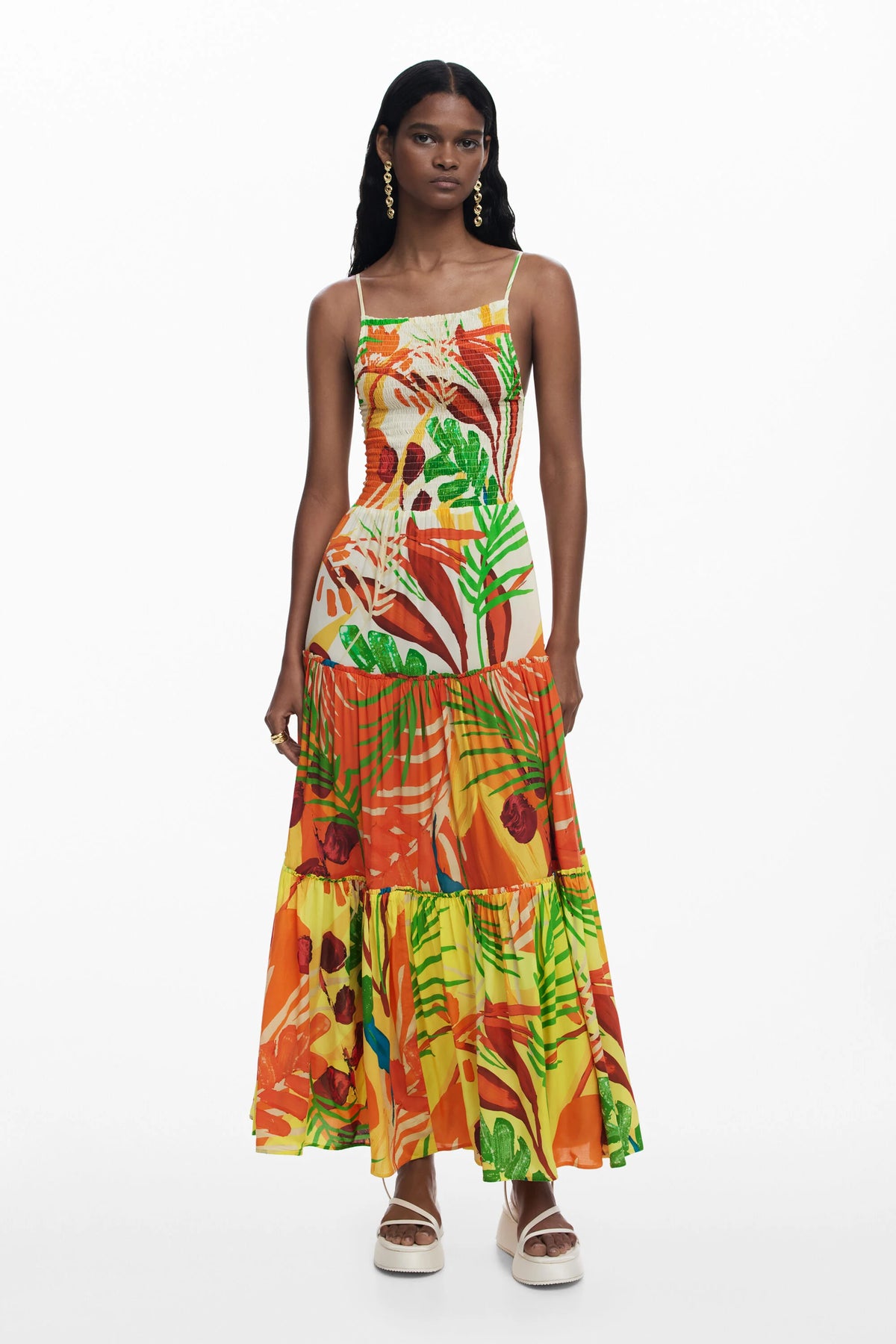 Model wearing a colorful tropical print dress on a white background