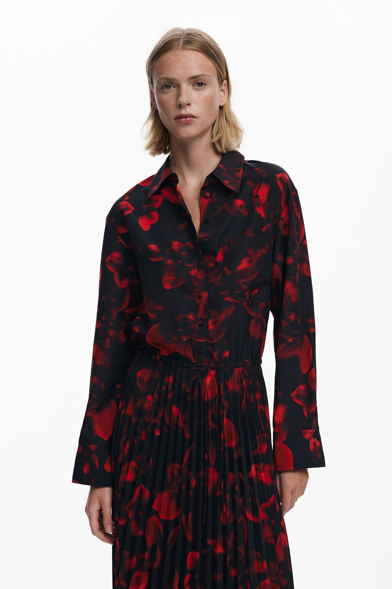 Woman wearing a black dress with red floral pattern on a white background