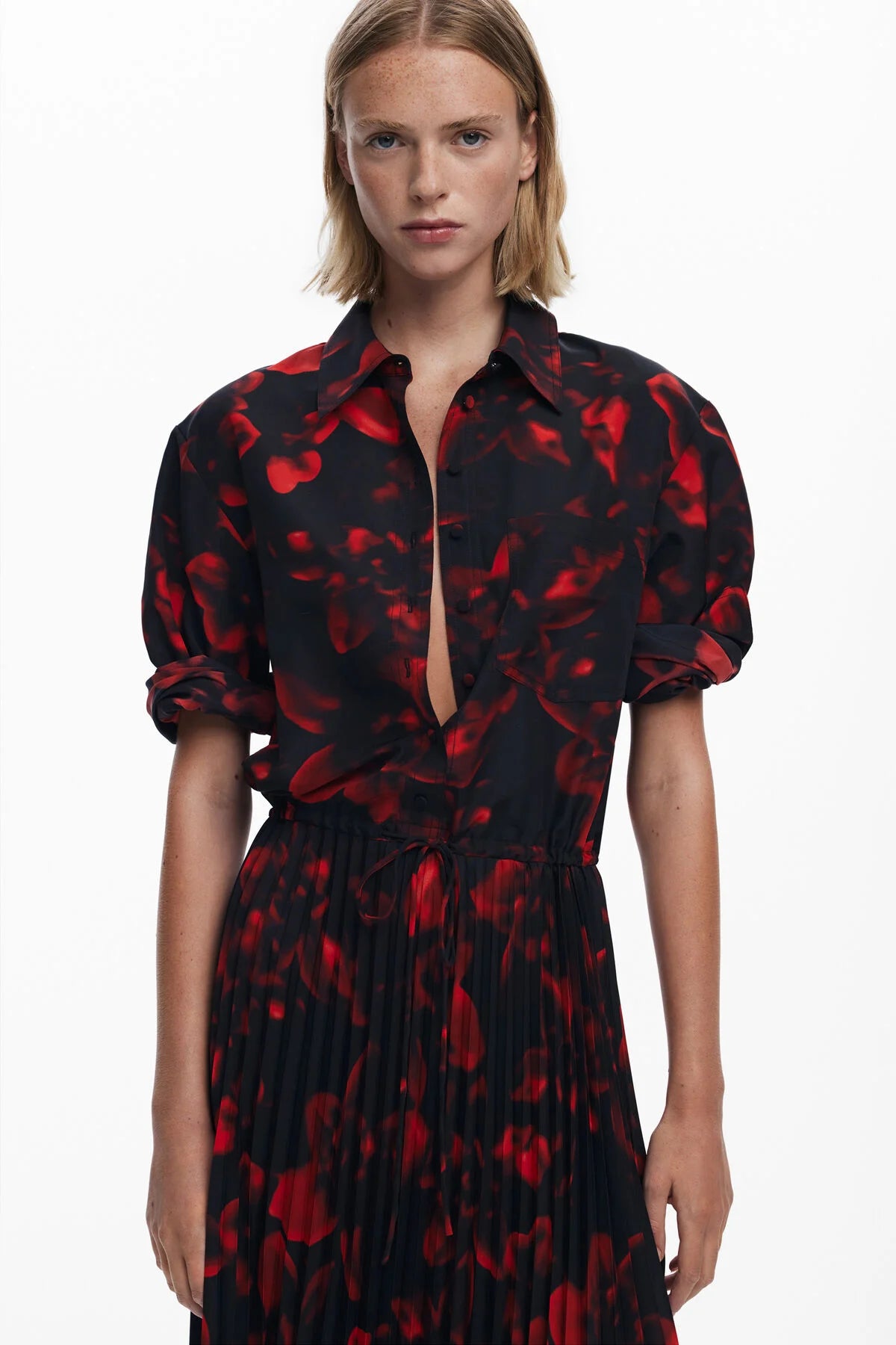 Woman wearing a black dress with red floral pattern on a white background