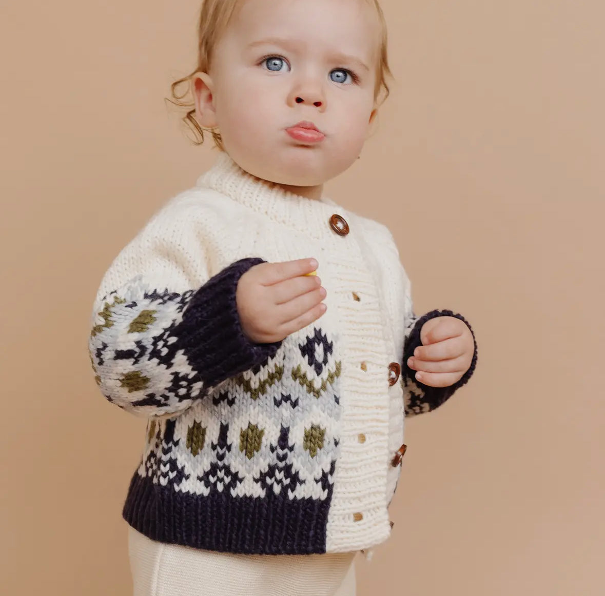 Child wearing a patterned sweater from The Blueberry Hill against a beige background. 