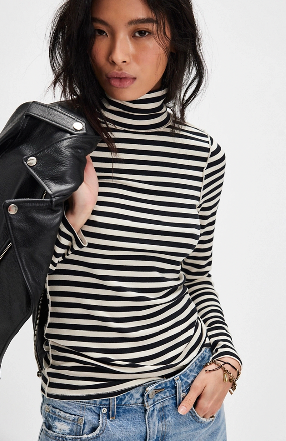 Person wearing a black and white striped turtleneck with a leather jacket on a white background