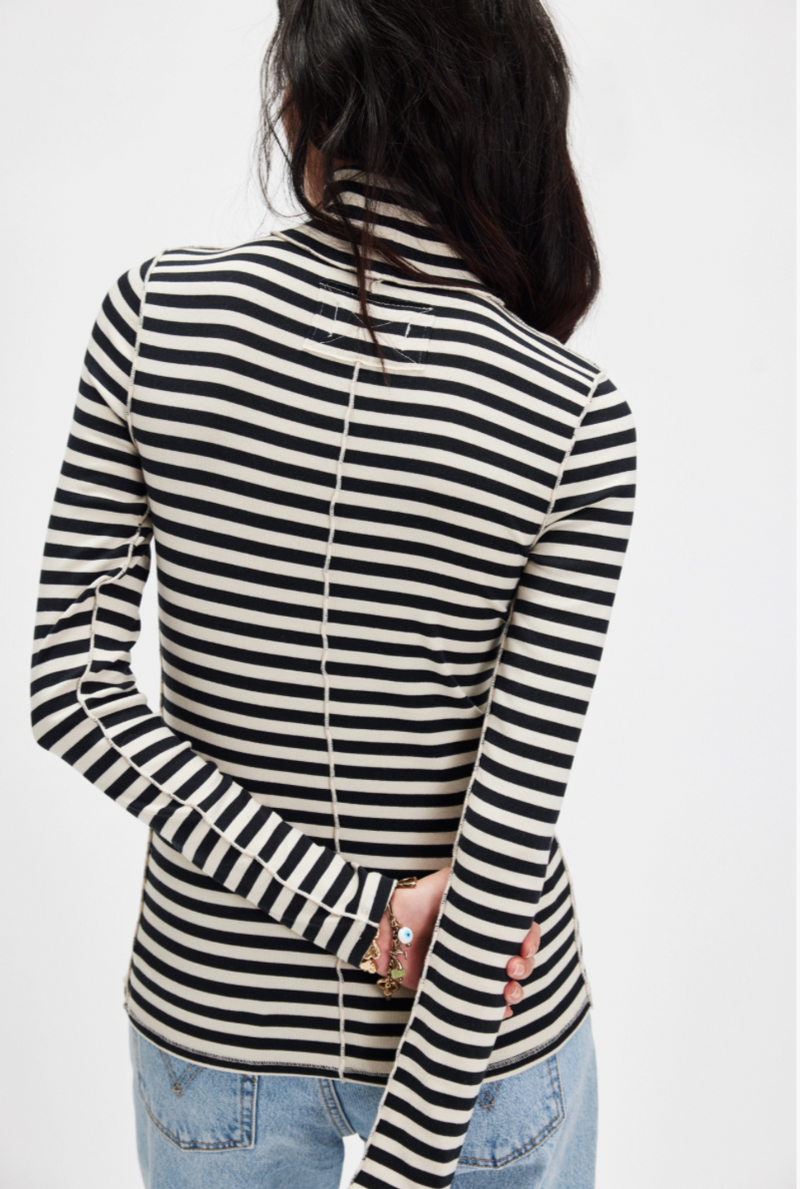 Person wearing a black and white striped long-sleeve top on a plain background