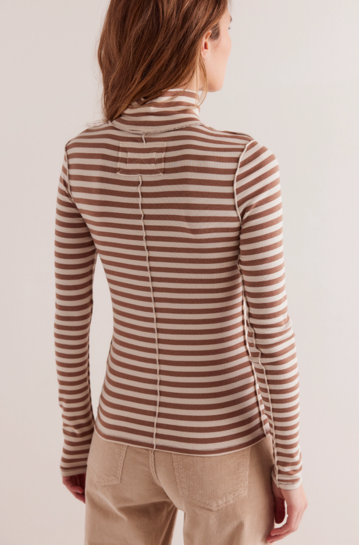 Person wearing a striped long-sleeve top and beige pants on a plain background