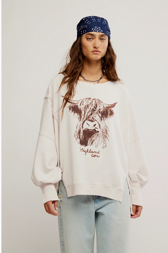 Person wearing a white sweatshirt with a cow graphic and 'Highland Cow' text, standing against a plain background.