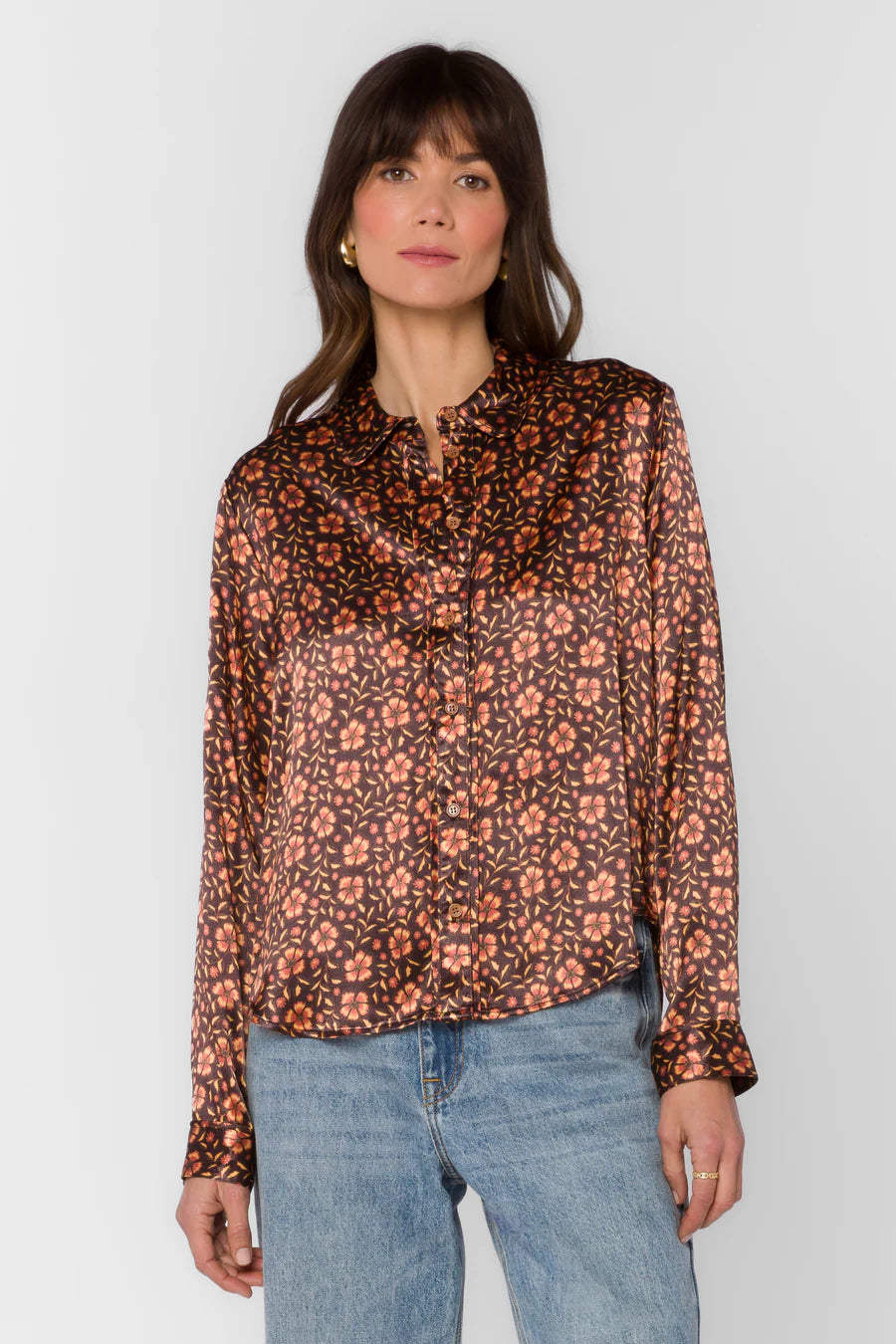 Woman wearing a floral blouse and jeans against a white background