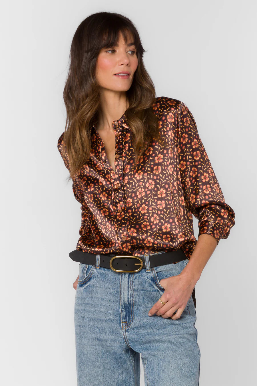 Woman wearing a floral blouse and jeans against a white background
