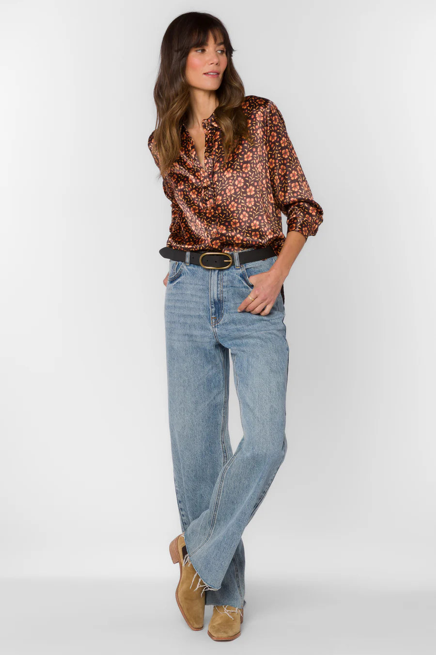 Woman wearing a patterned blouse and jeans on a white background