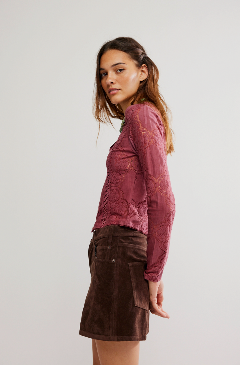 Woman wearing a pink lace top and brown skirt on a white background