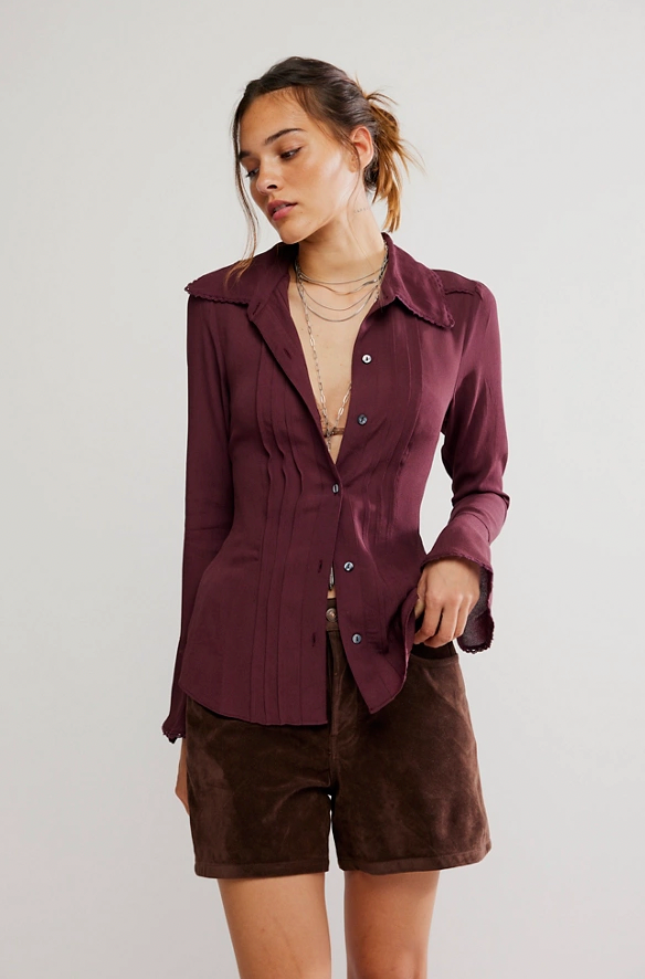 Woman wearing a burgundy shirt and brown shorts on a plain background