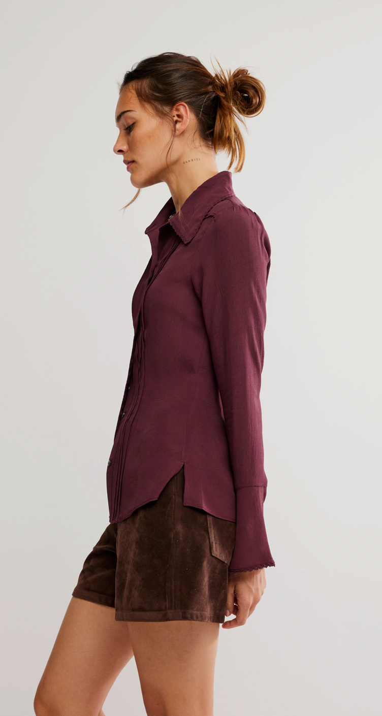 Woman wearing a burgundy shirt and brown shorts on a plain background
