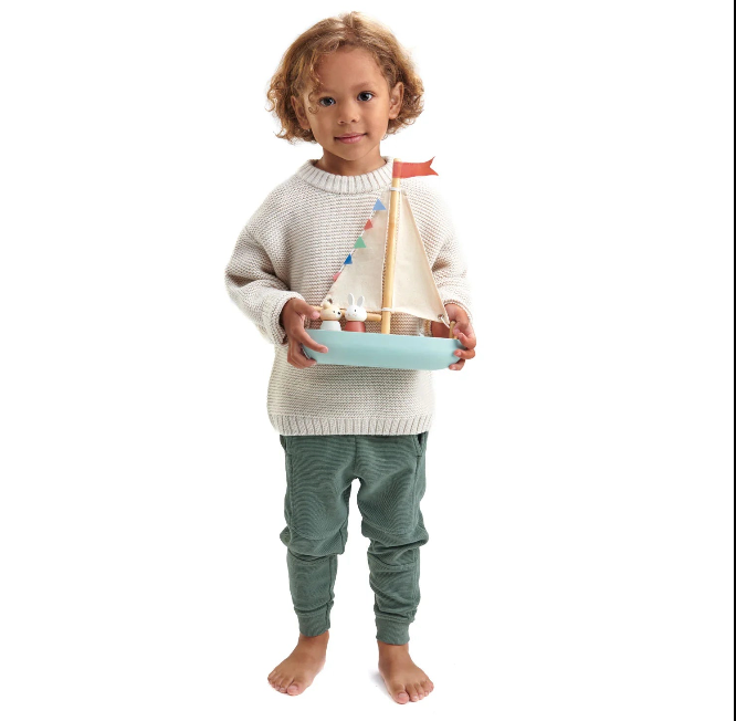 Child holding a toy sailboat on a white background