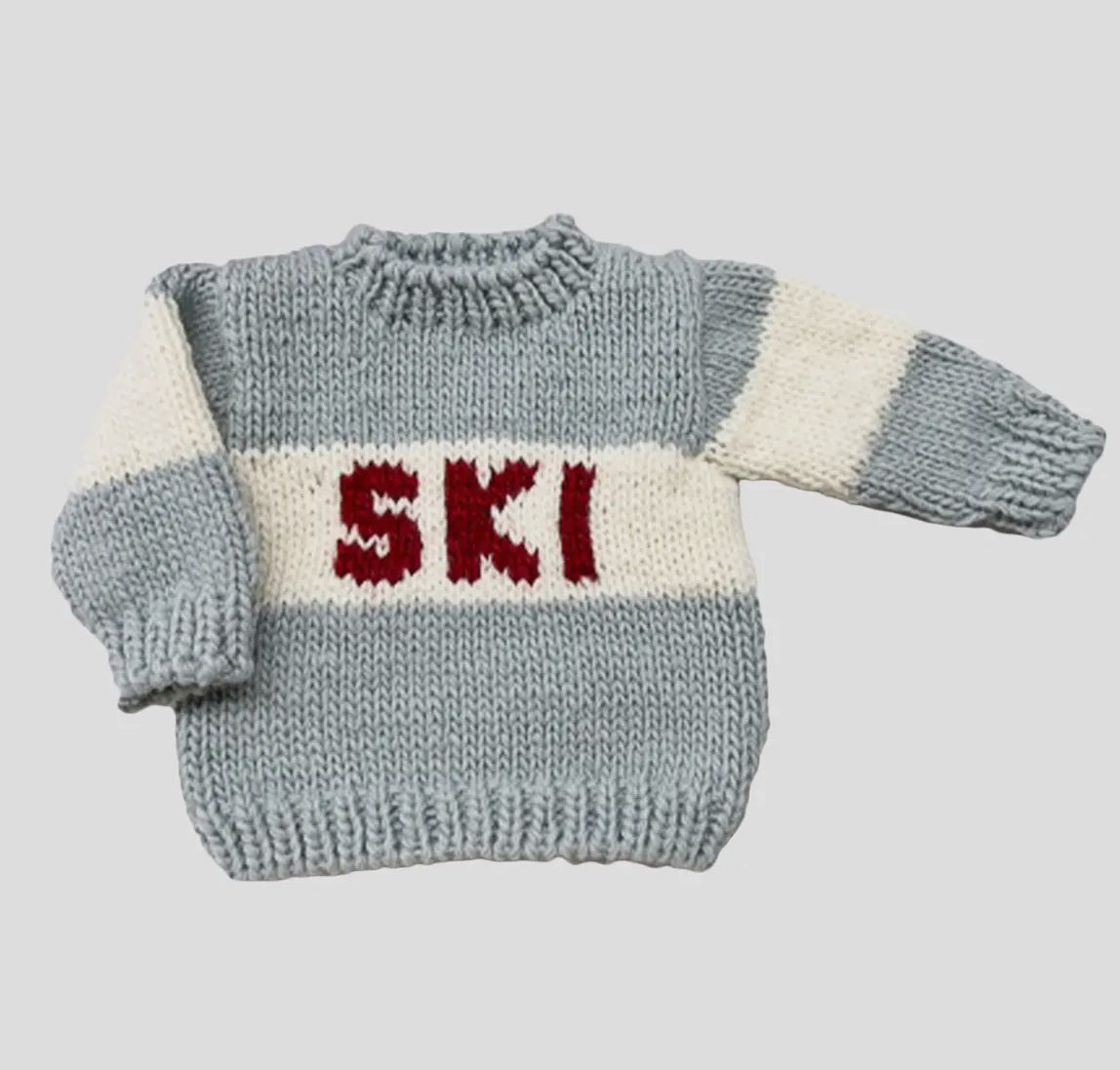 Baby knitted sweater with 'SKI' text on a light gray background from Blueberry Hill. 