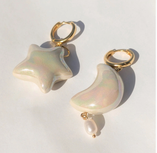 Star and moon-shaped earrings with pearl accents on a white background