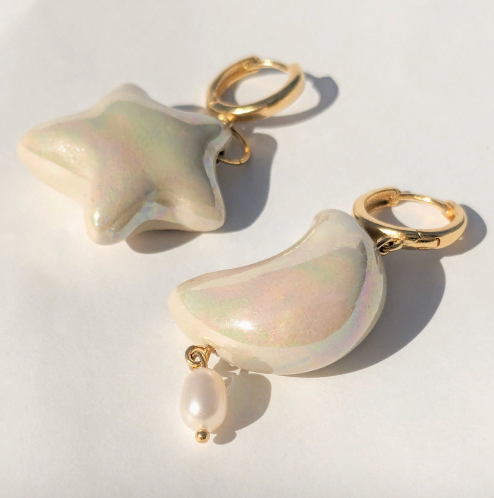 Star and moon-shaped earrings with pearl accents on a white background