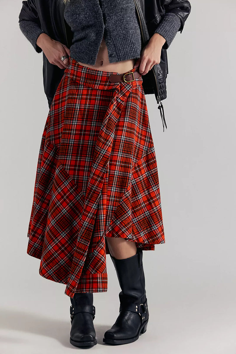 Person wearing a Free People red plaid skirt with black boots on a plain background