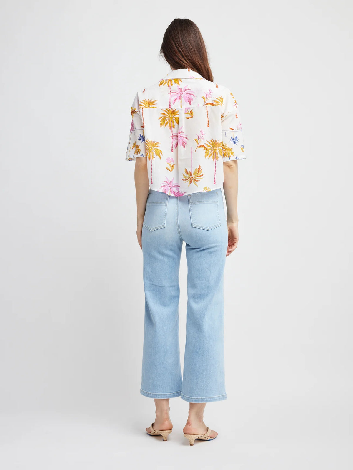Person wearing a floral shirt and light blue jeans on a white background
