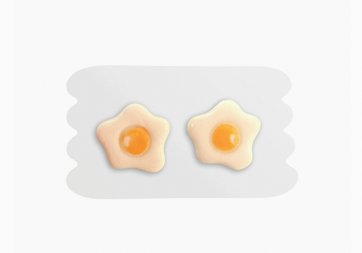 Star-shaped earrings resembling sunny-side-up eggs on a white background