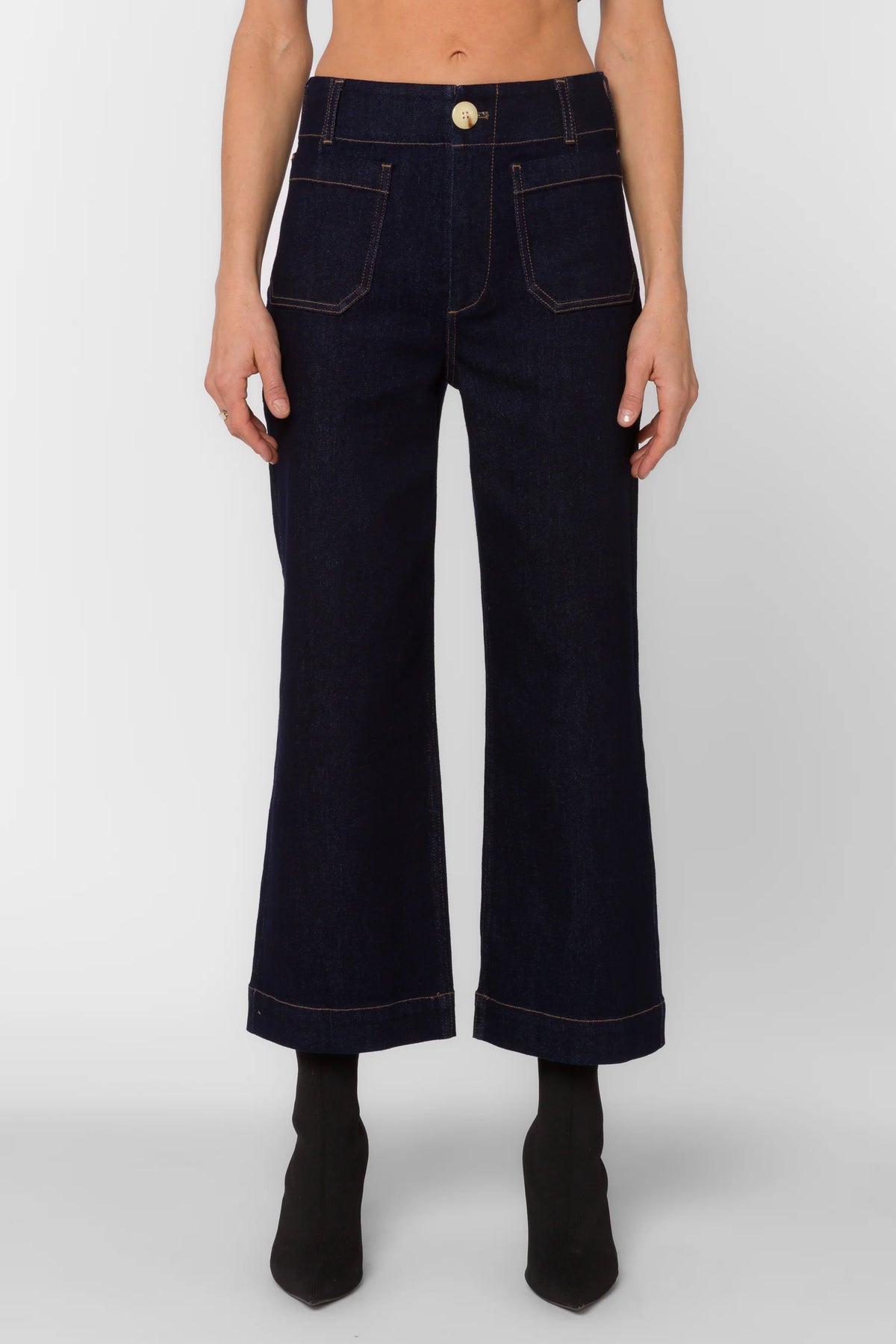 Person wearing dark blue jeans on a plain background