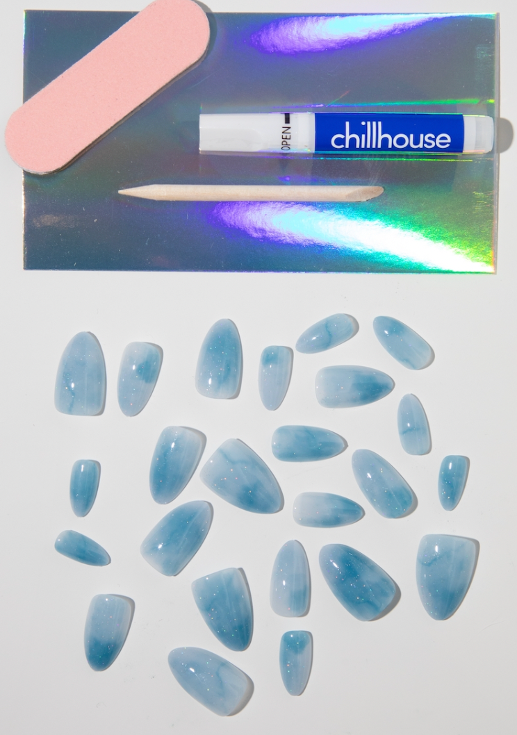 Set of blue nail extensions with a bandage and 'chillhouse' product in the background