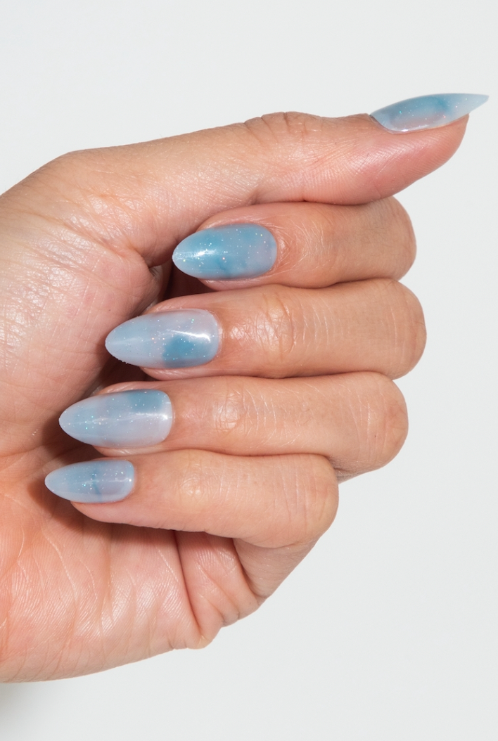 Hand with light blue nail polish on a white background