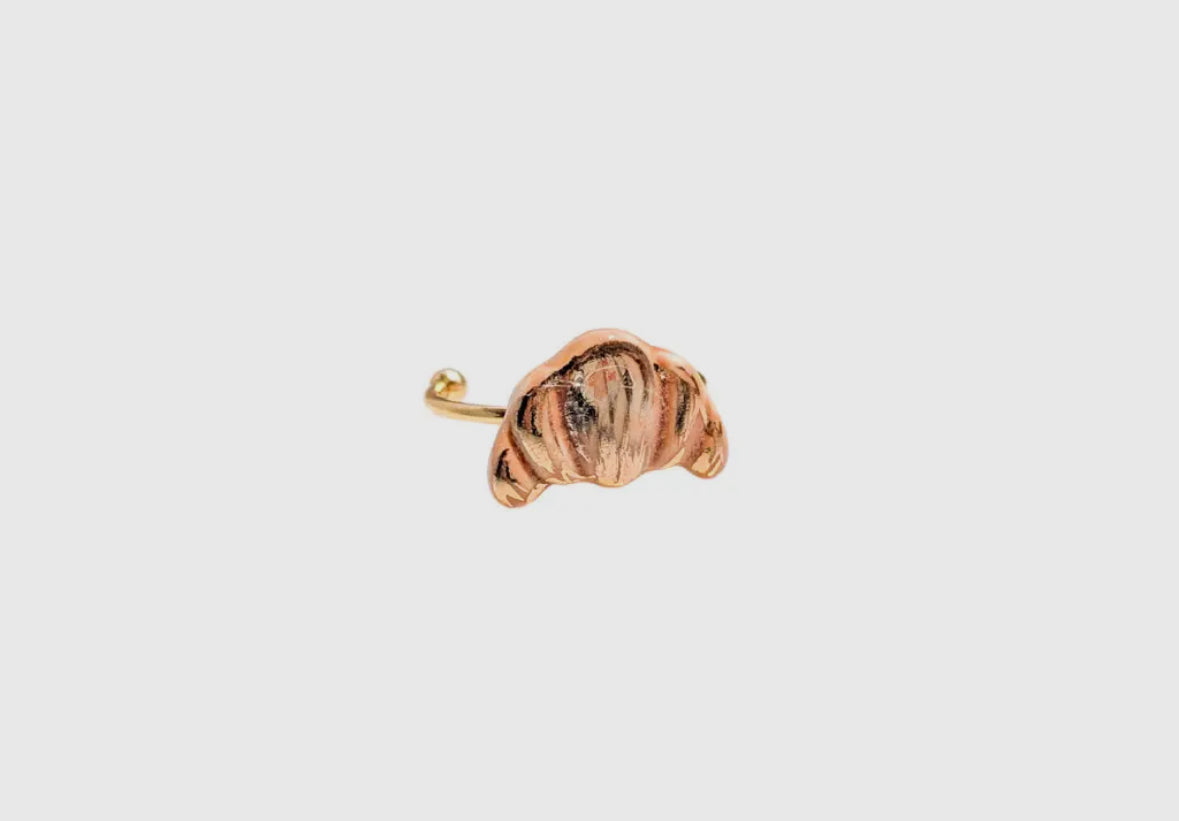 Gold earring with a textured design on a light gray background