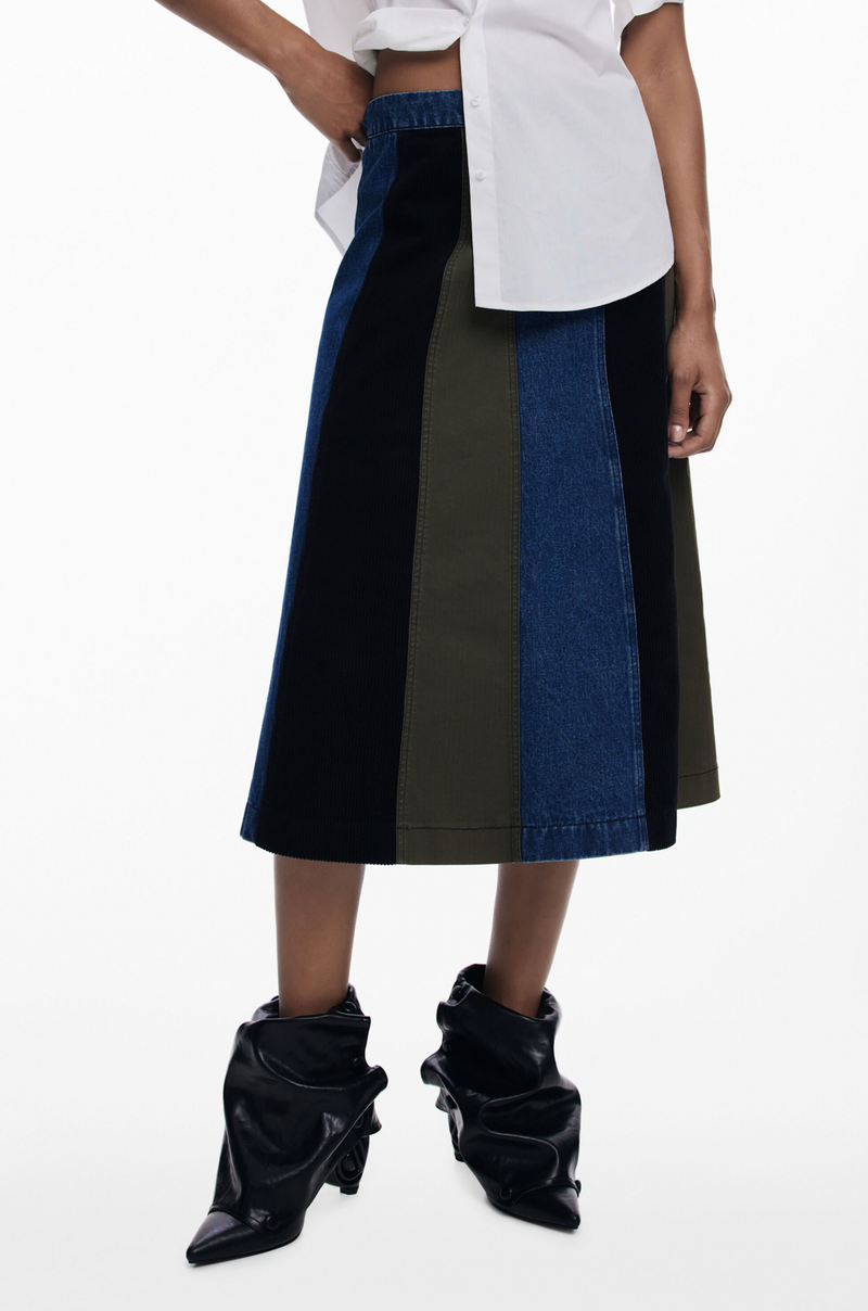 Person wearing a black and blue color-blocked skirt with a white top on a white background