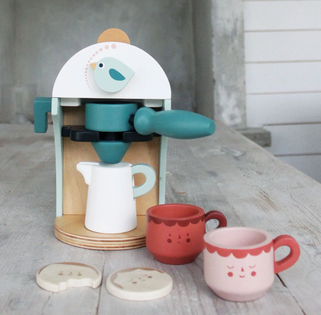 Children's toy coffee maker set with cups and a bird design on a wooden surface.