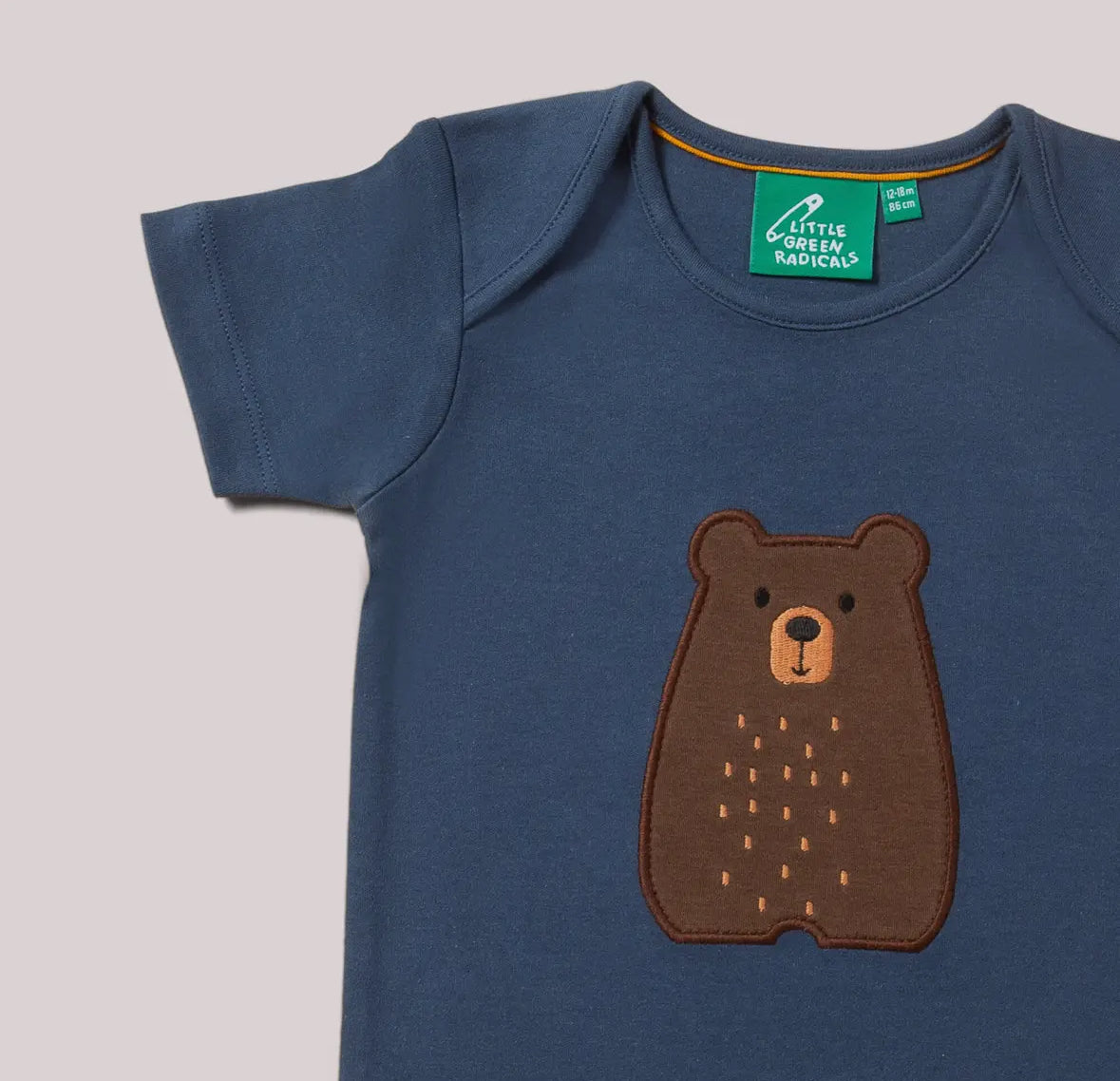 Blue baby t-shirt with a brown bear design and a visible brand tag on a light gray background