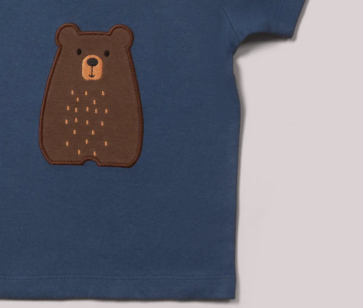 Blue shirt with a brown bear patch on a light gray background
