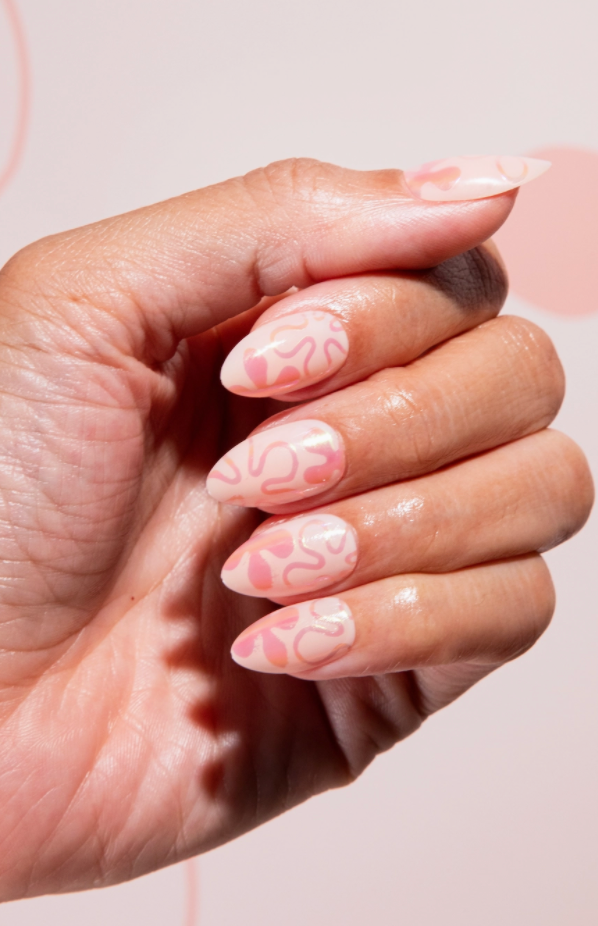 Hand with pink floral nail design on a light pink background