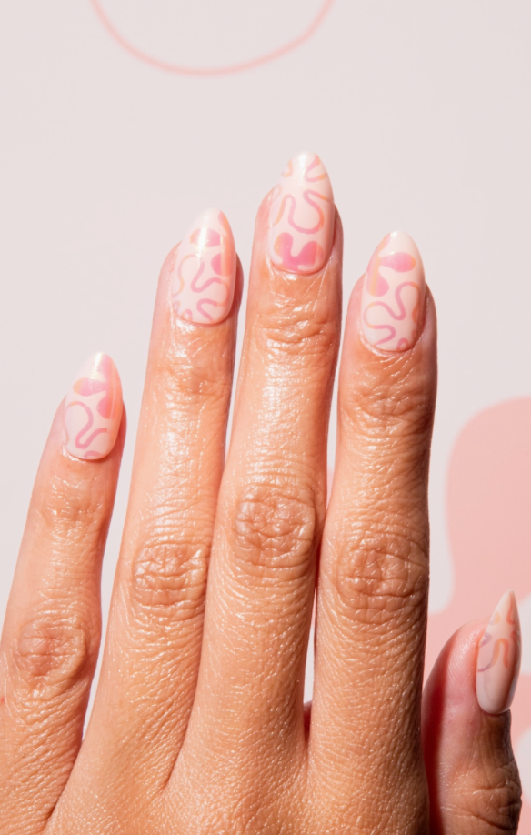Close-up of a hand with pink nail polish on a light pink background