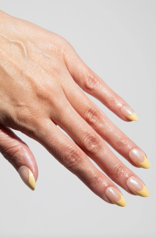 Hand with light-colored nail polish on a plain background