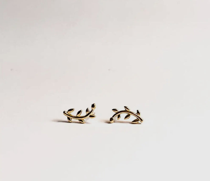 Gold leaf-shaped earrings on a light gray background