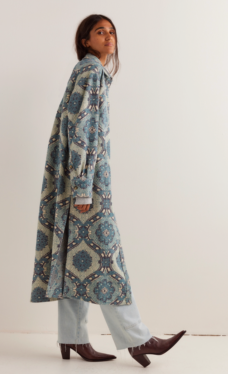 Woman wearing a long, patterned blue and gray coat against a white background