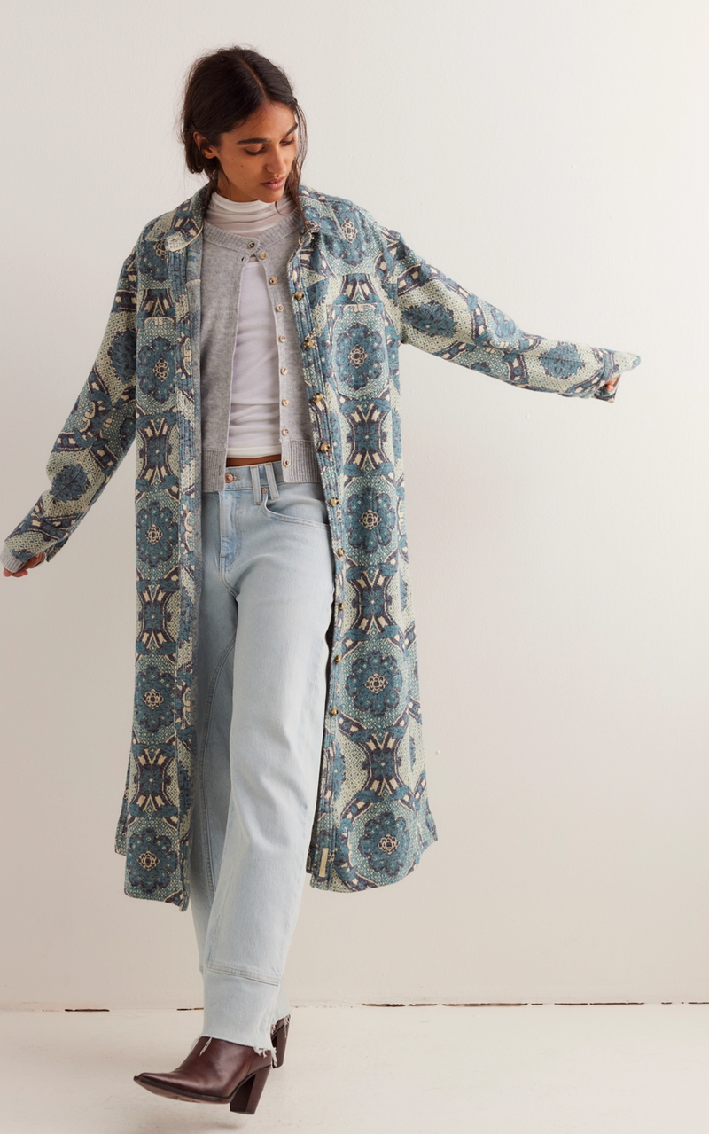 Woman wearing a long, patterned coat on a white background