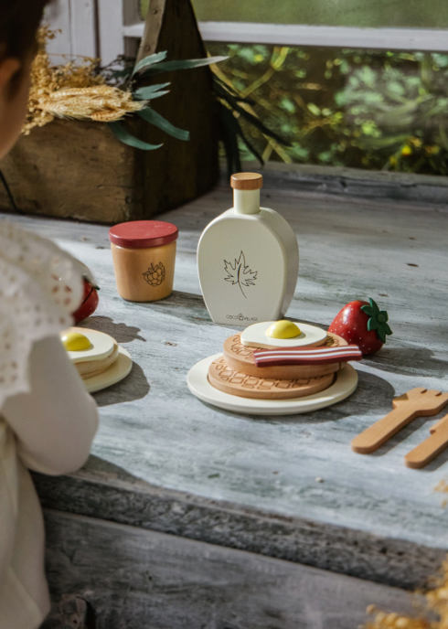 Children's playset with miniature food items and a bottle on a wooden surface.
